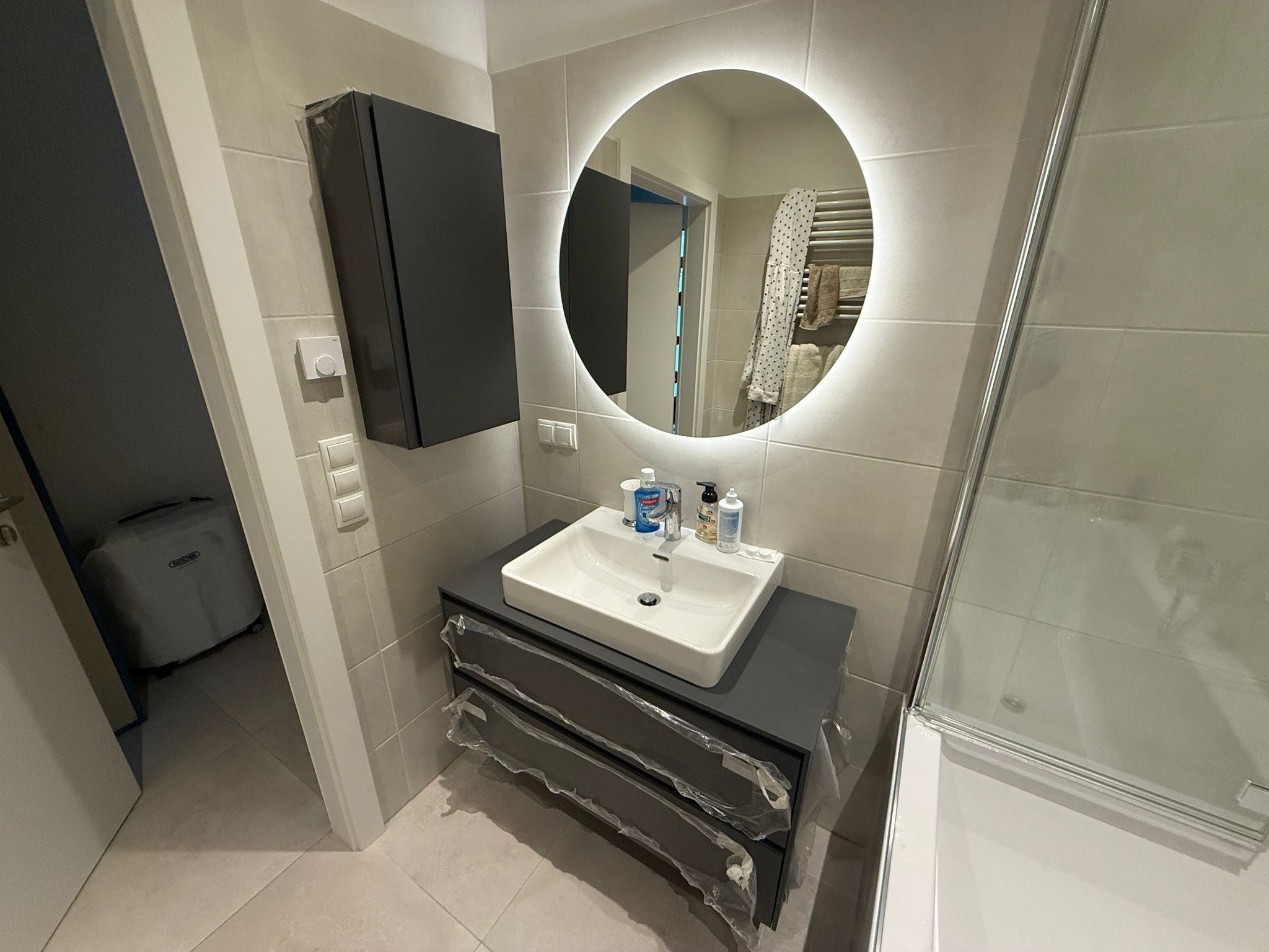 Installation eines beleuchteten runden LED-Spiegels und modernem Waschtisch-Unterschrank in Wien – Sanitärservice Wien