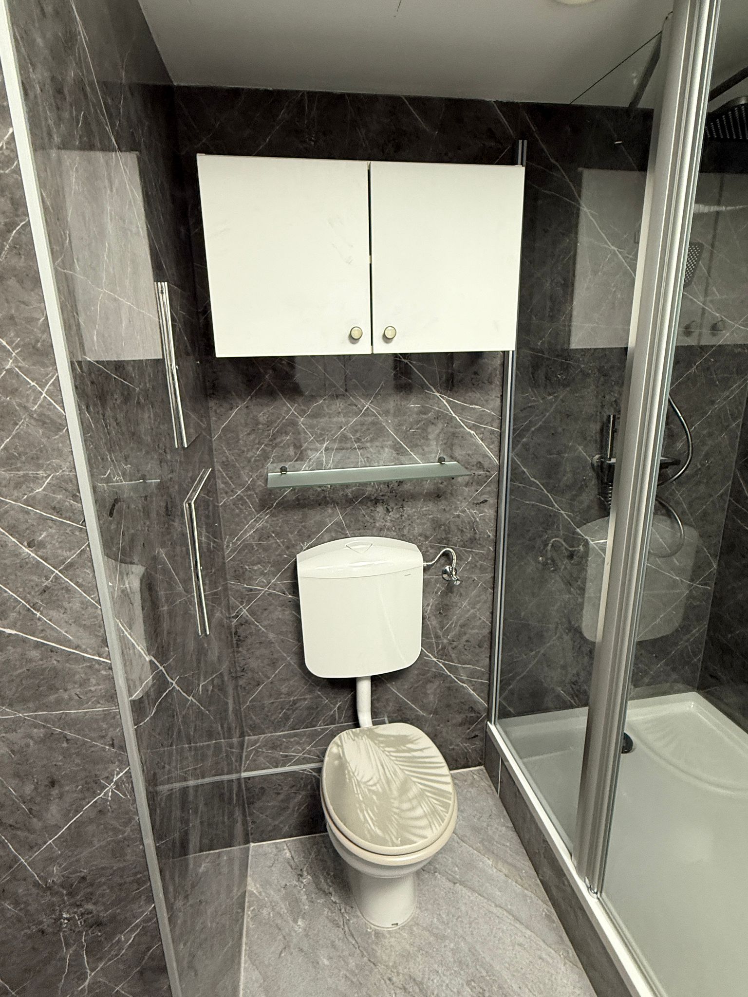 Sichere Wandmontage eines weißen Oberschranks und Glasablage im Badezimmer Wien – Sanitärservice Wien